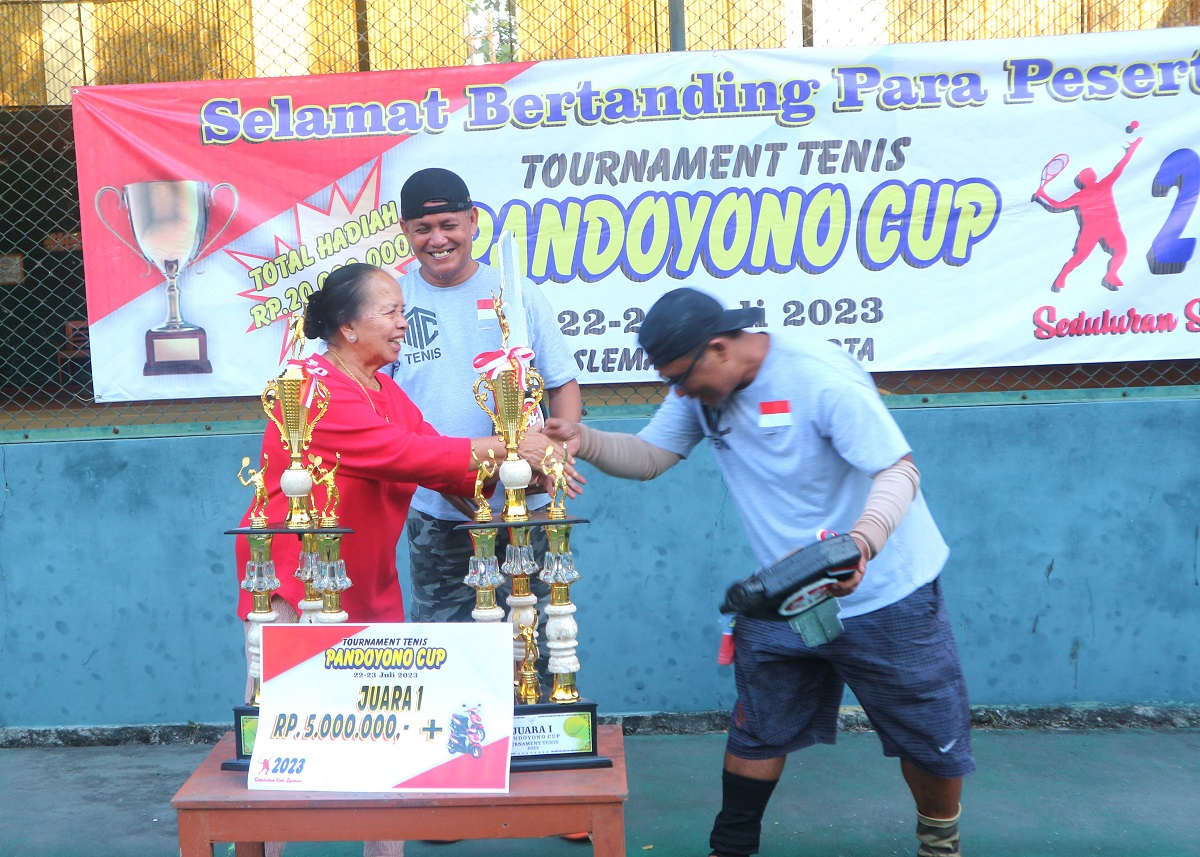 Ibu Mukidah Pandoyono menyerahkan hadiah pada Juara 1 Turnamen Tenis Internal Pandoyono 2023 di Lapangan Tenis Kalisoko, Kulonprogo. (foto : heri purwata)