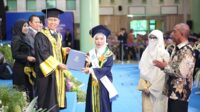 Prof Hari Purnomo menyerahkan ijazah dan Pin Emas kepada wisudawati terbaik yang disaksikan kedua orangtuanya. (foto : istimewa)